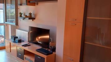 Una sala de estar moderna con un televisor grande, muebles de madera y un amplio armario.