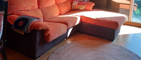 A modern living room with a sectional sofa, a round rug, and a large window with blinds.