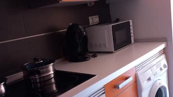 A kitchen with a stove, microwave, and washing machine.