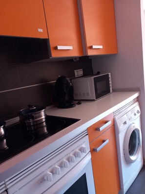Une cuisine équipée d’une cuisinière, d’un four à micro-ondes et d’un lave-linge.