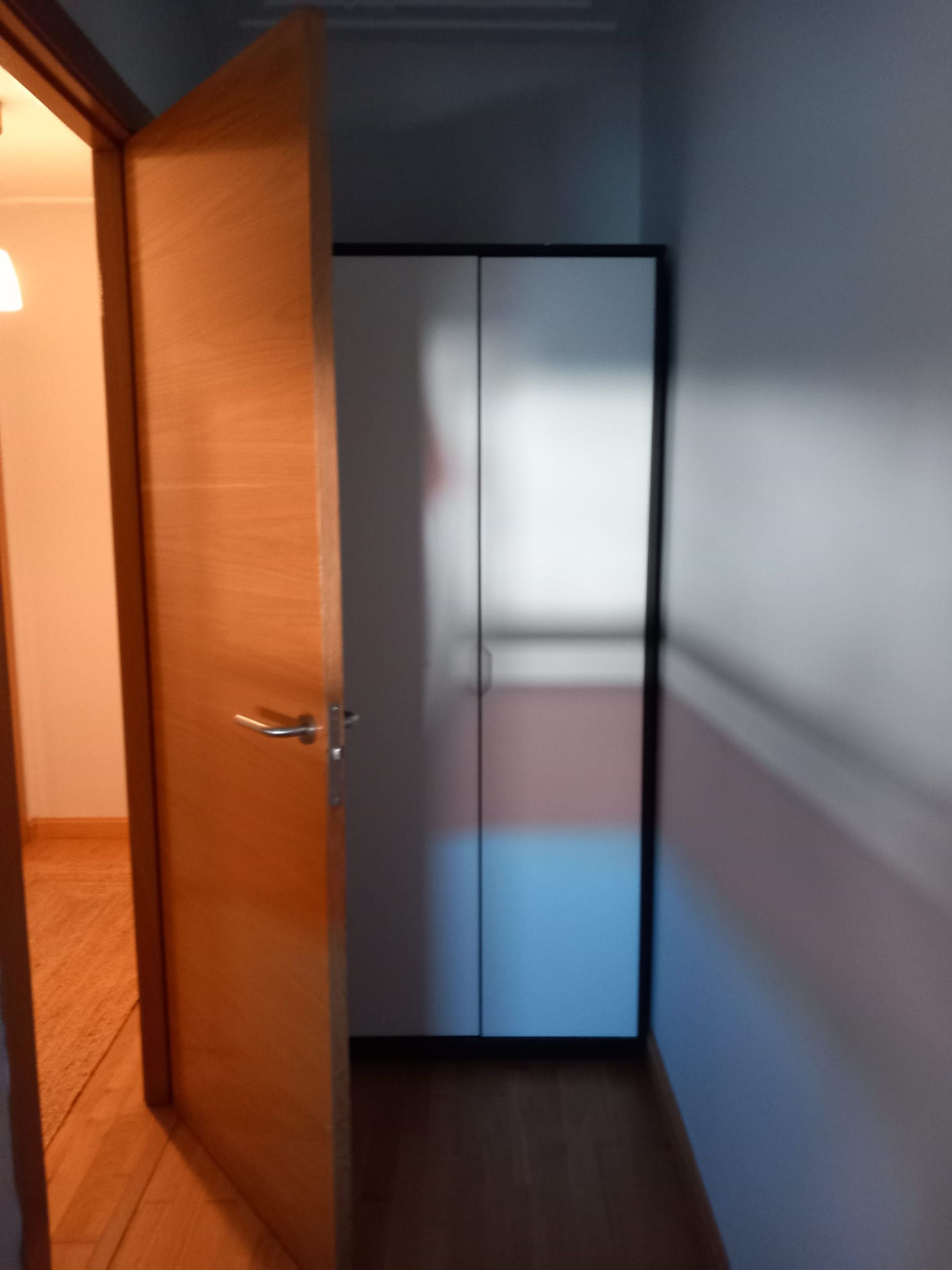 Ein Zimmer mit einer Holztür und einem Kleiderschrank mit zwei Türen.