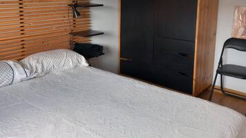 A bedroom with a bed, a wooden headboard, a wardrobe, and a chair.