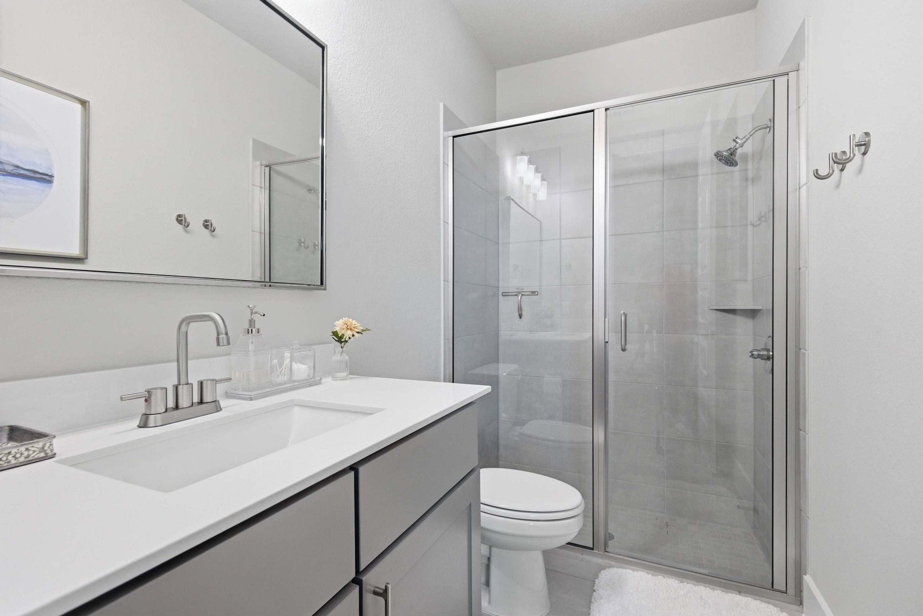 A modern bathroom with a glass shower enclosure, a white sink with a faucet, and a toilet.