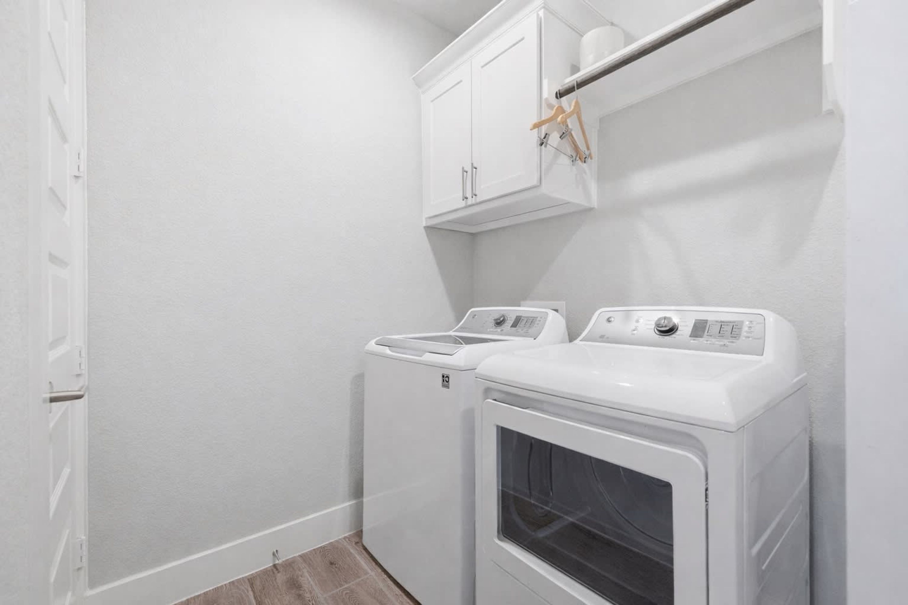 A laundry room with two front-loading washing machines and a cabinet above.