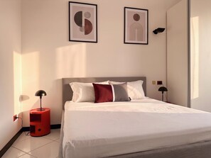 Ein modernes Schlafzimmer mit einem Bett, zwei Wandleuchten und zwei gerahmten Kunstwerken.