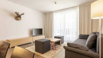 Una sala de estar moderna con sofá, reposapiés, mesa de centro y televisor de pantalla plana.