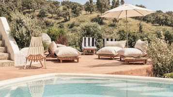 A poolside area with lounge chairs and a large umbrella.