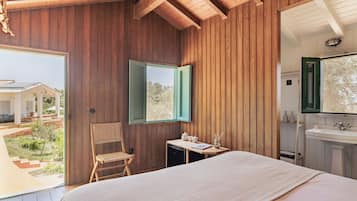 Une chambre à coucher avec un lit, une chaise, une petite table avec quelques objets, et une salle de bain avec un lavabo.