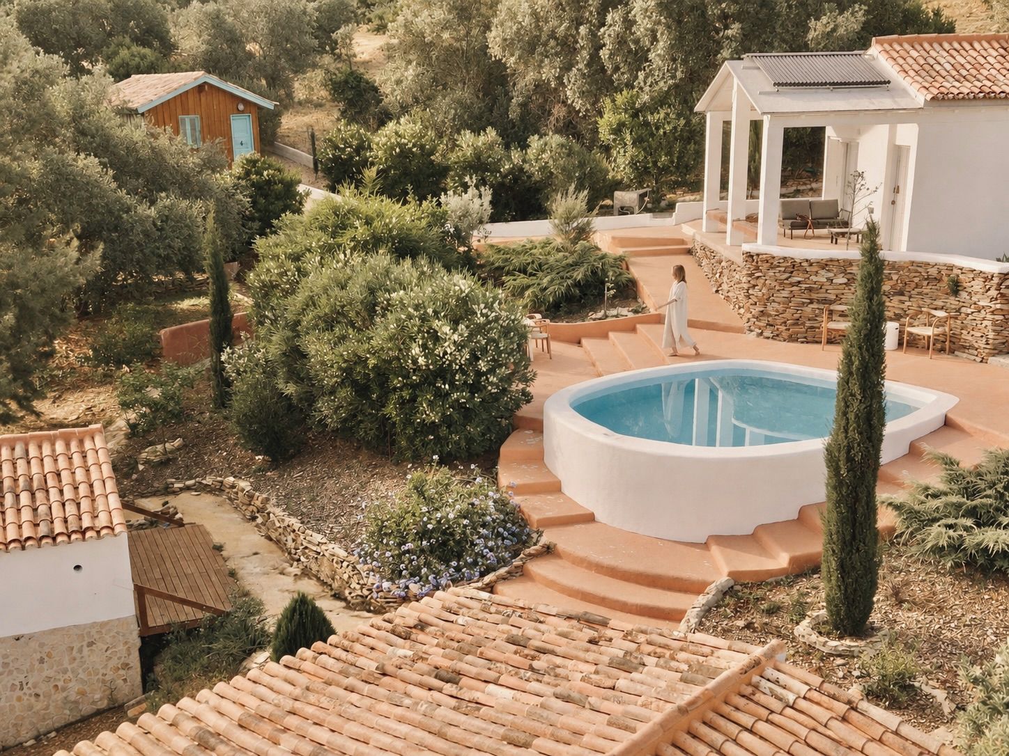 A pool area with steps leading to it, surrounded by greenery and stone walls.