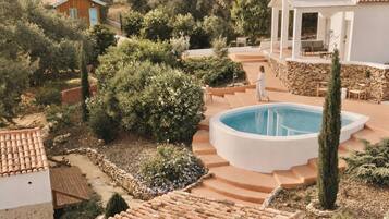 A pool area with steps leading to it, surrounded by greenery and stone walls.