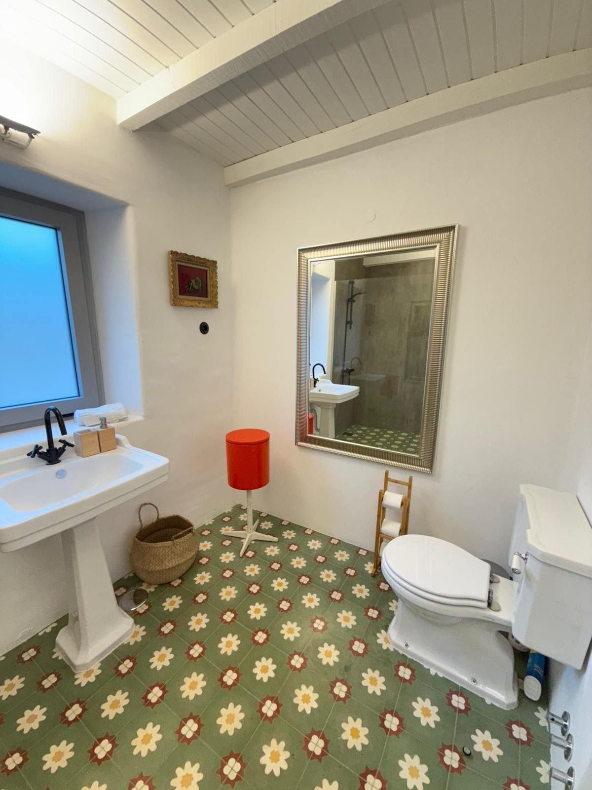 Ein Badezimmer mit einem weißen Waschbecken, einer Toilette, einer Dusche und einem Spiegel.