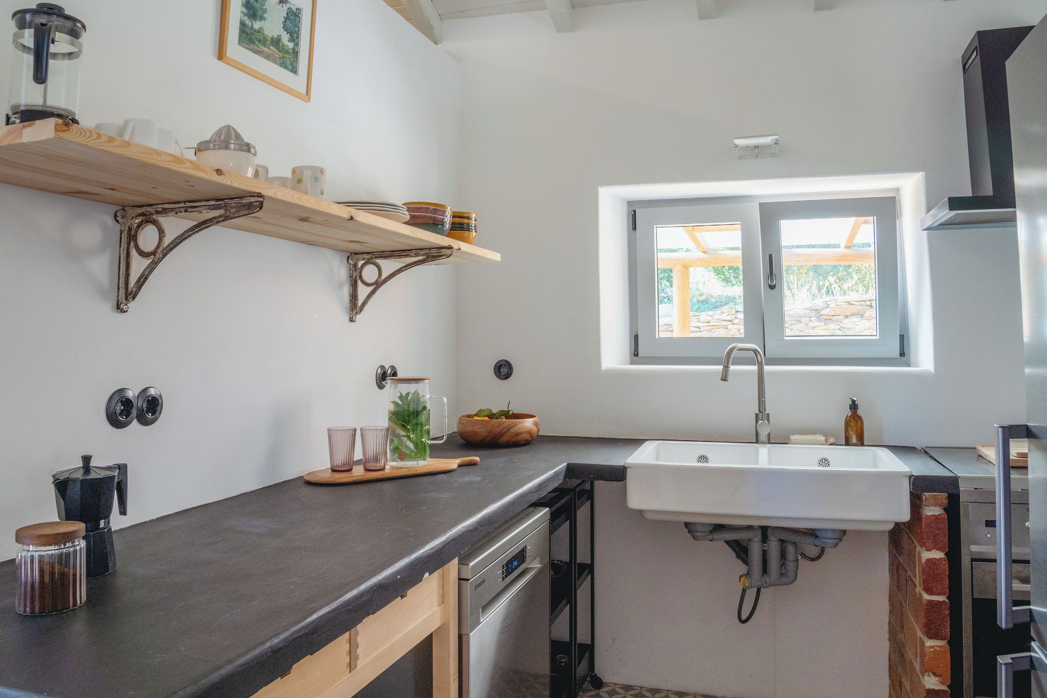 Una cucina con lavastoviglie integrata, una finestra vista e un piano di lavoro con diversi oggetti.