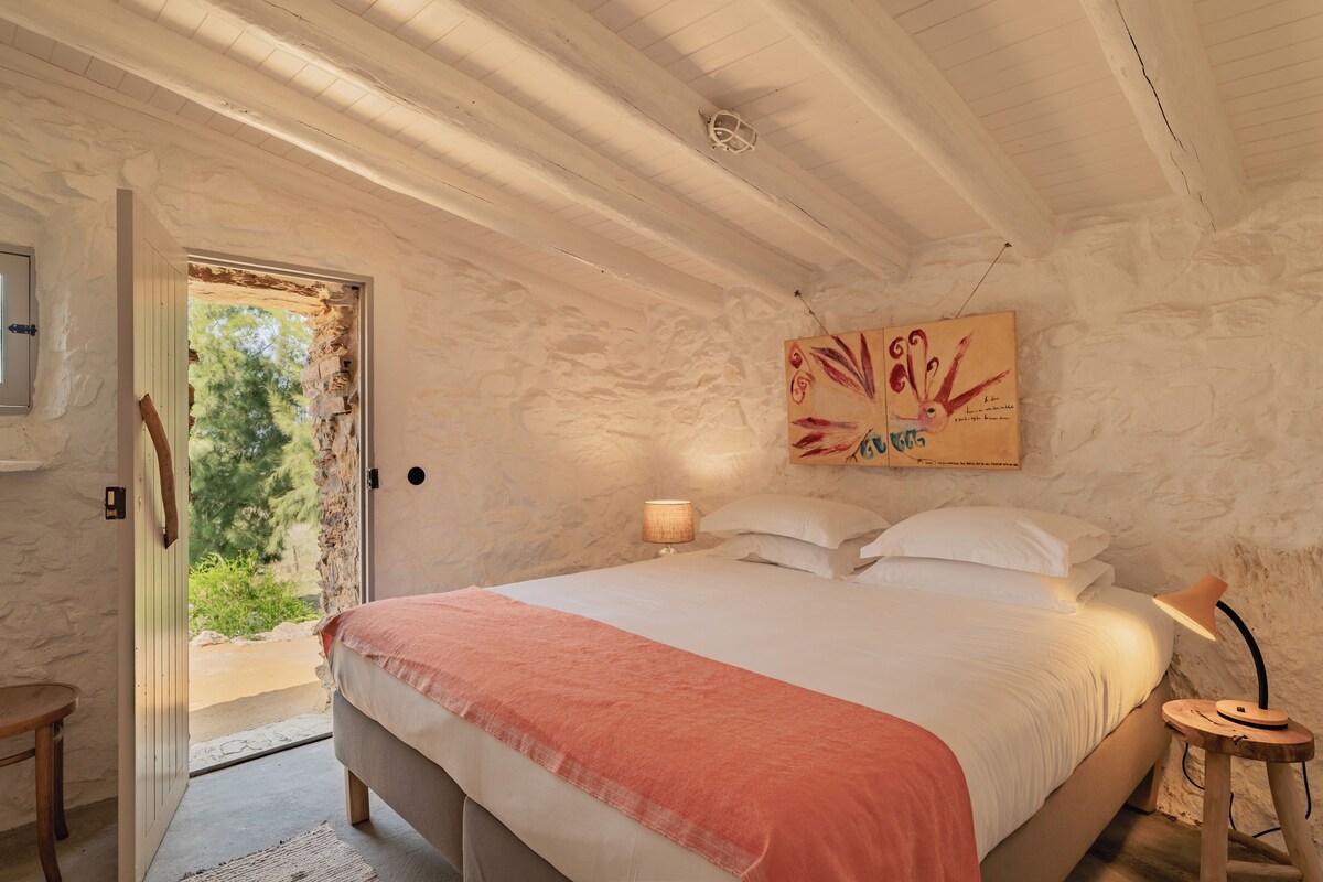 Un dormitorio con una cama, una mesita de noche, una lámpara y un cuadro en la pared.