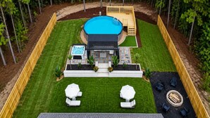 Un jardin avec une piscine, un jacuzzi et un espace salon extérieur.
