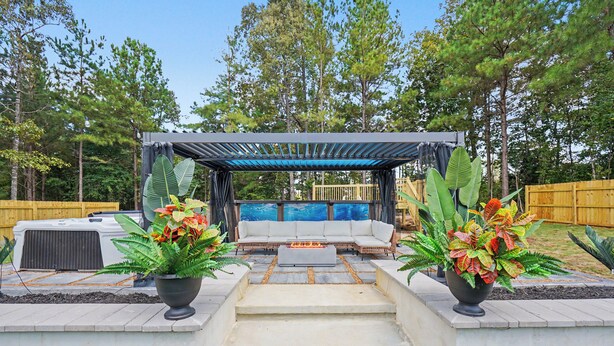 Un espace patio doté d’un coin salon abrité, d’un foyer et de plantes en pot.