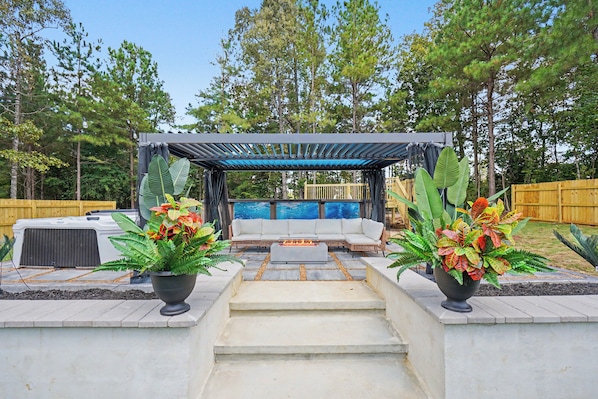 A patio area with a covered seating arrangement, a fire feature, and potted plants. - 4Bedroom 3 Bath Athletes Retreat minutes near the Rome Tennis Center! Pool Hot Tub + Spa (Rome)