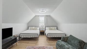 Ett sovrum med två sängar, en tv, en soffa och en mönstrad matta.