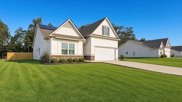 A residential property with a well-maintained lawn, a single-story house with a garage, and a neighboring house.