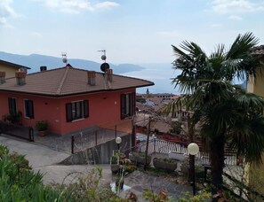 A residential building with a red facade, a tiled roof, and a balcony with a railing. - Tignale-olzano, Apt. 1 (Tignale)