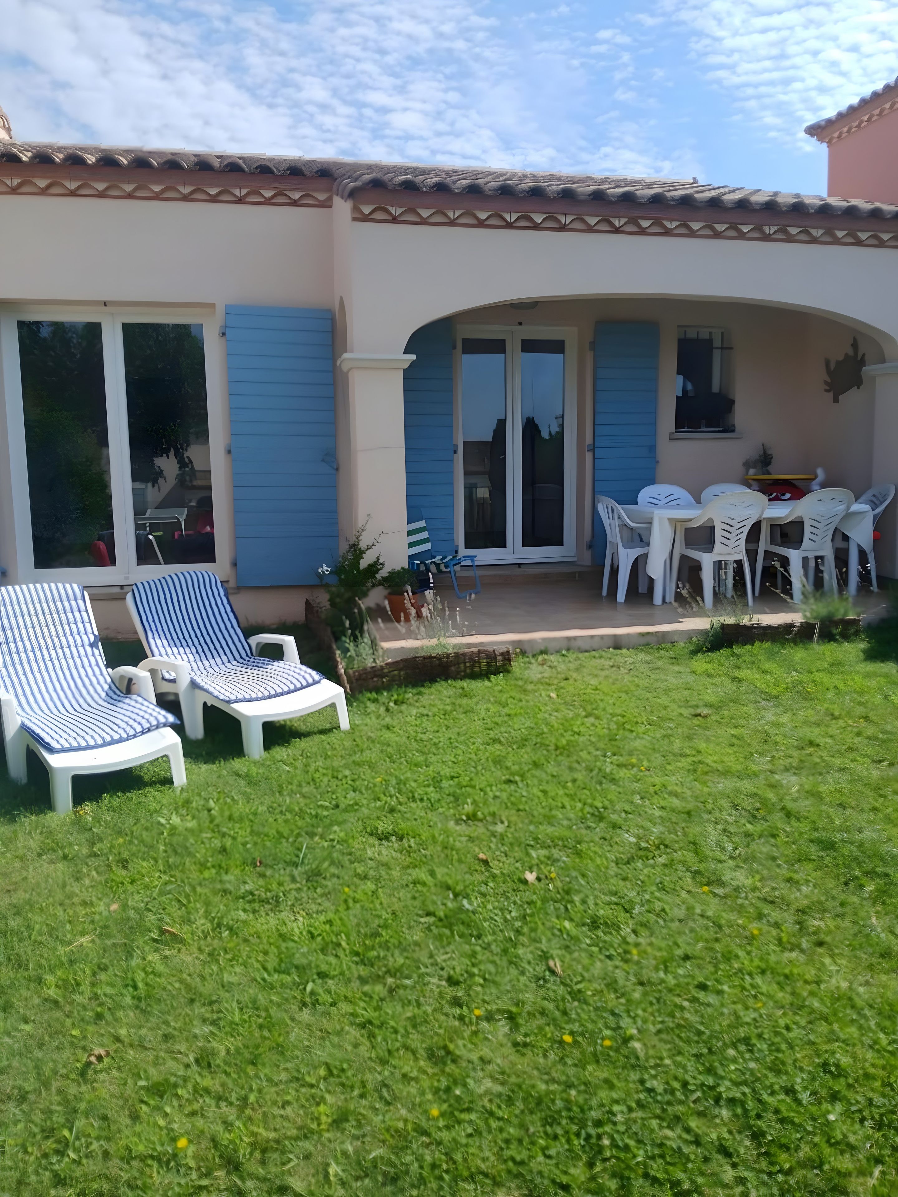 Une maison dotée d’un patio aménagé avec du mobilier d’extérieur et d’un espace salon couvert.