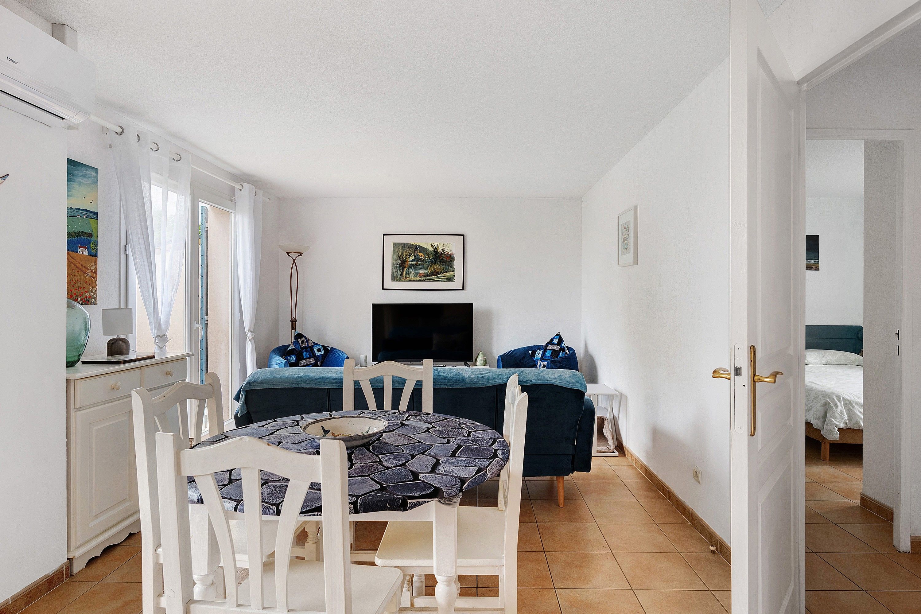 Une pièce de taille modeste comprenant une table à manger, des chaises, un lit et un téléviseur.