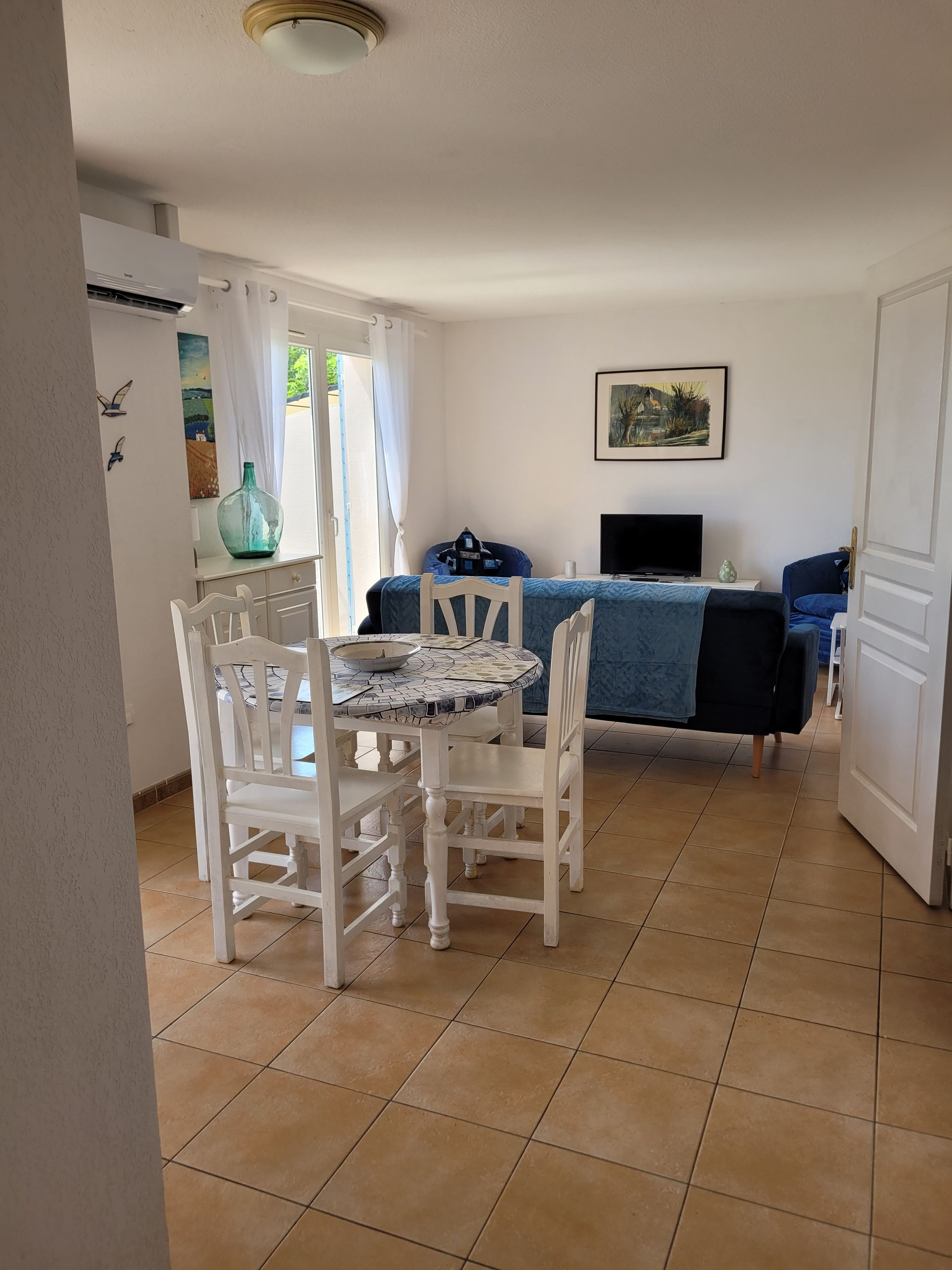 Una habitación con una mesa de comedor, sillas, un sofá, un televisor y un cuadro en la pared.