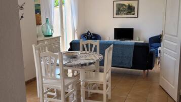 Una habitación con una mesa de comedor, sillas, un sofá, un televisor y un cuadro en la pared.