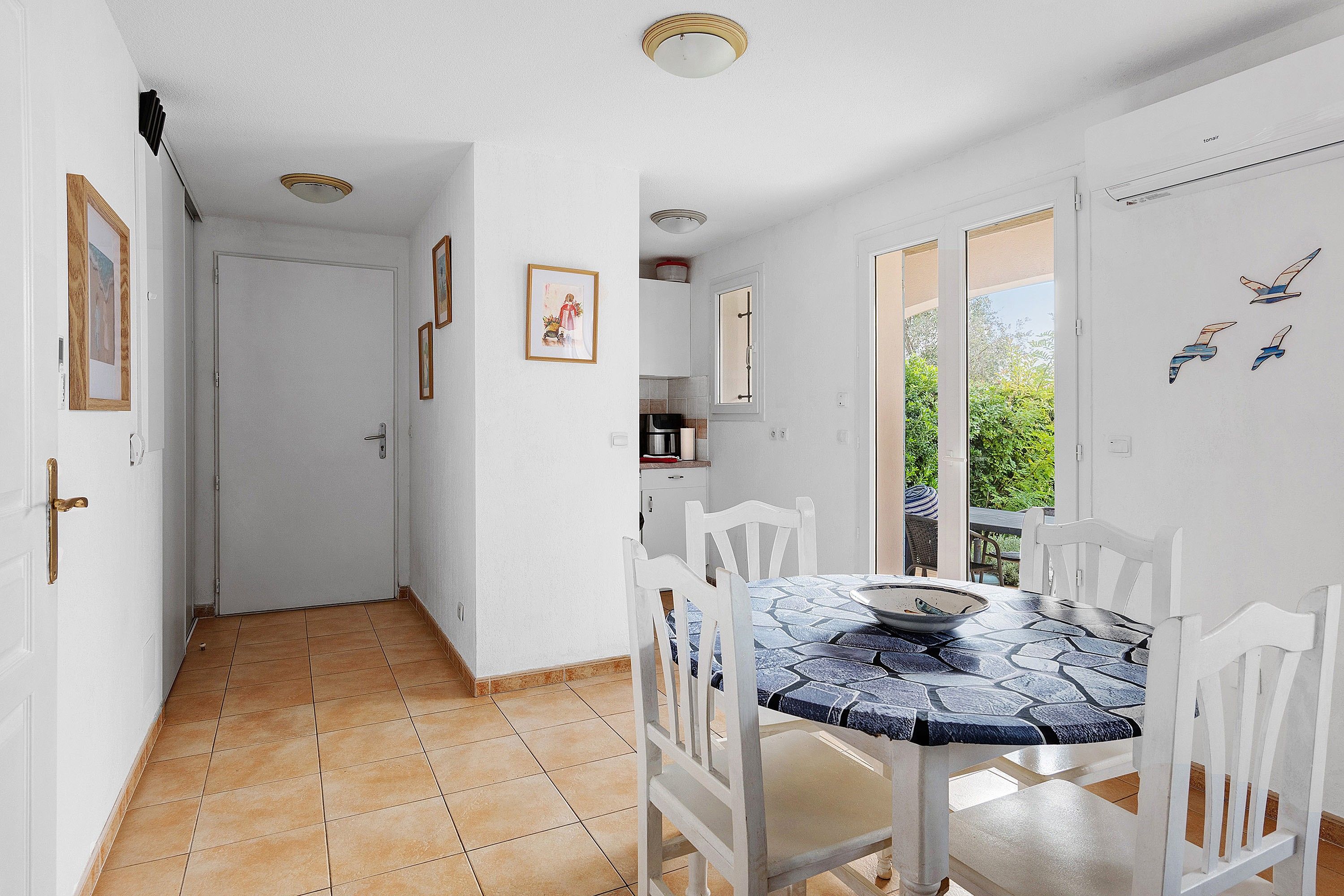 A dining area with a tiled floor, white walls, and a table with chairs.
