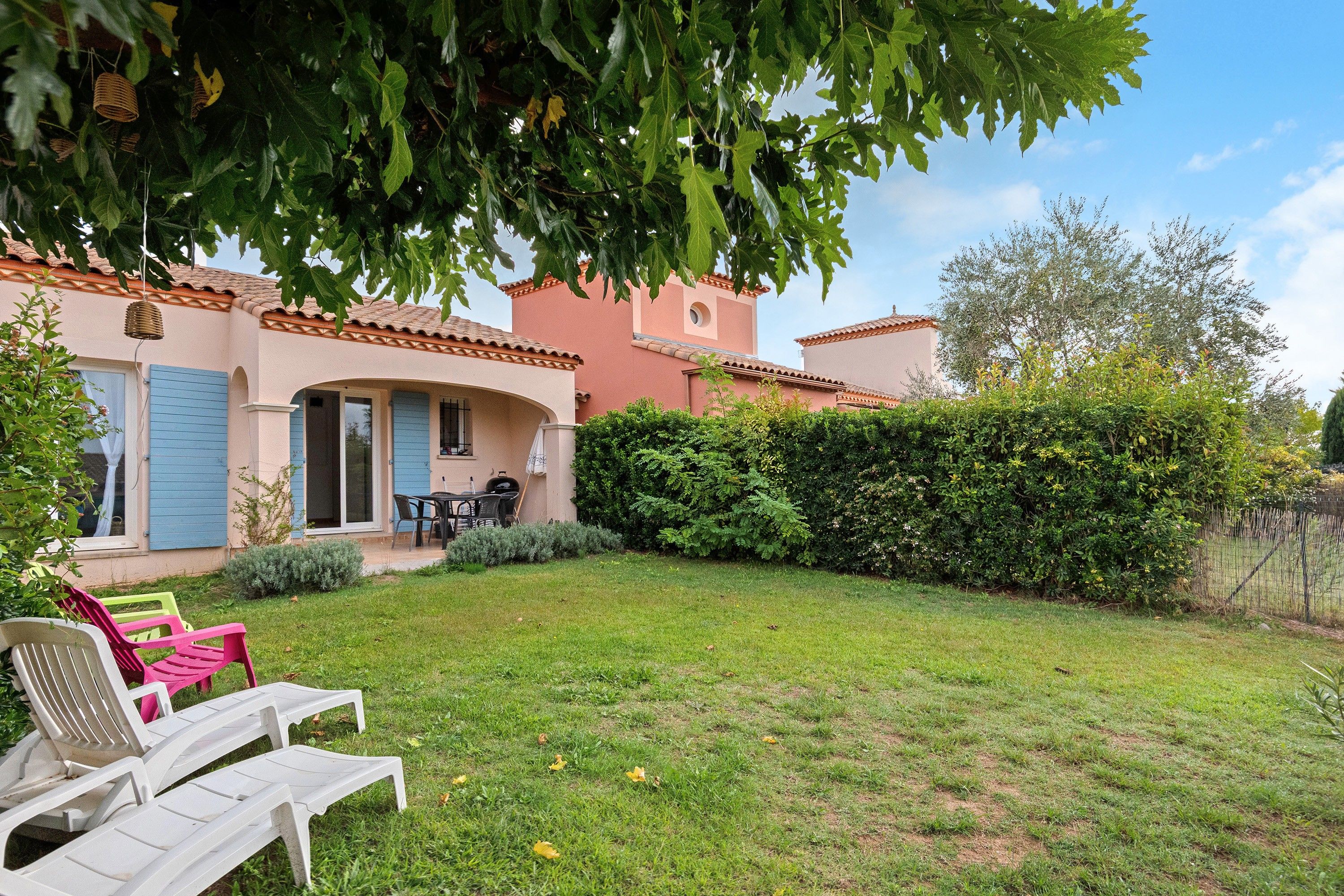 Una casa con patio, mobili da giardino e un prato curato.