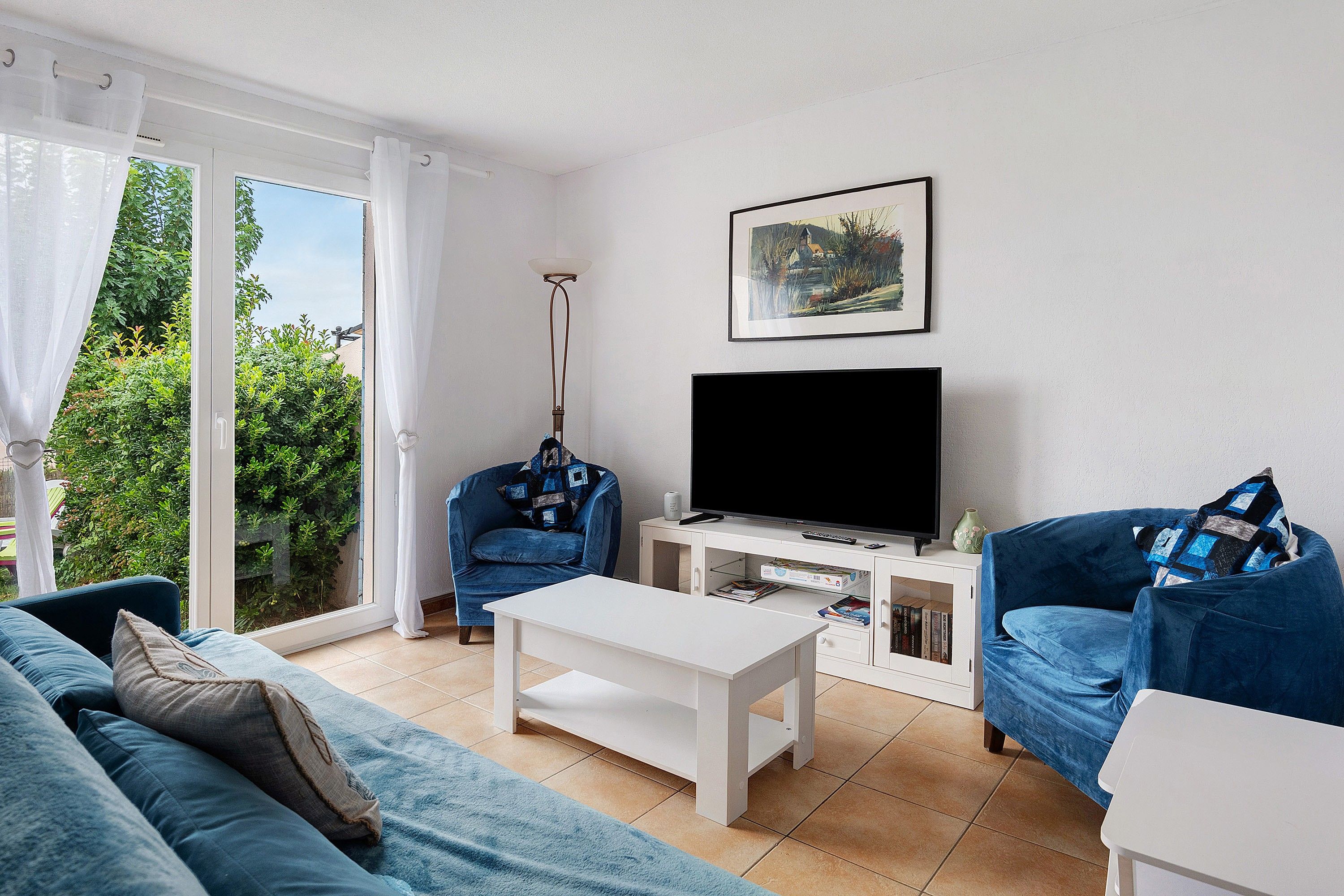 Ein Wohnzimmer mit einer Couch, einem Couchtisch, einem Fernseher und einem Bücherregal.