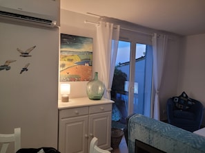 Une pièce comprenant un lit, un bureau, une lampe, un tableau et une fenêtre avec des rideaux.