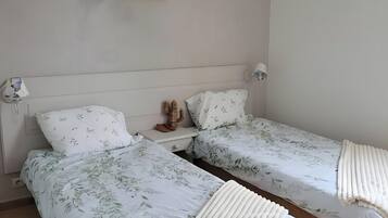 Ein Schlafzimmer mit zwei Einzelbetten, einem Nachttisch, einer Kakteen-Dekoration und einem gerahmten Bild an der Wand.