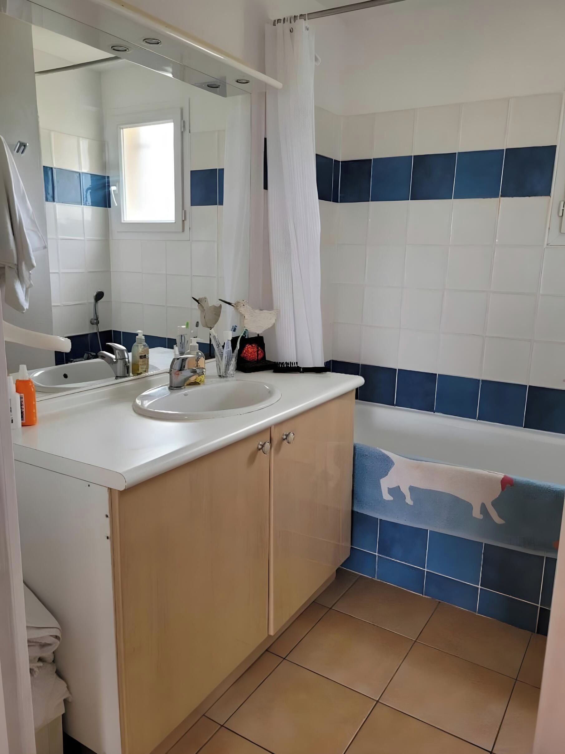 A bathroom with a sink, mirror, and shower curtain.