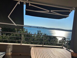 En balkon med udsigt over en sø og fjerne bakker.