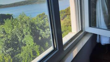Ein Fenster mit Blick auf ein Gewässer und viel Grün.