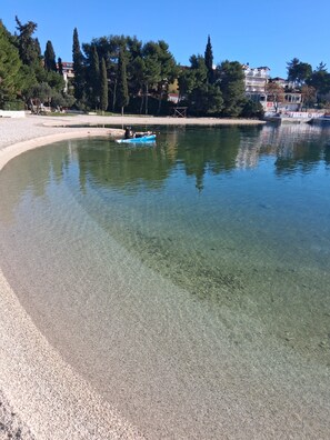 Ein klarer See mit einem Boot und einem Kiesstrand.