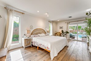 Ein Schlafzimmer mit Bett, Nachttisch und Blick auf einen Swimmingpool.