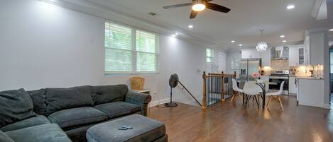 A spacious living room with a sectional sofa, a dining area with a glass table, and a kitchen with modern appliances.