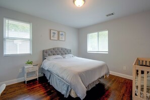 A bedroom with a large bed, two bedside tables, a nightstand, a crib, and two windows with blinds. - < 1 Mi to Marta! Extended Getaway 3 Mi to Dtwn (Atlanta)