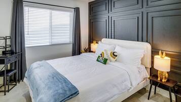Ein Hotelzimmer mit einem Bett, Nachttischlampen, einem Schreibtisch und einem Fenster mit Vorhängen.