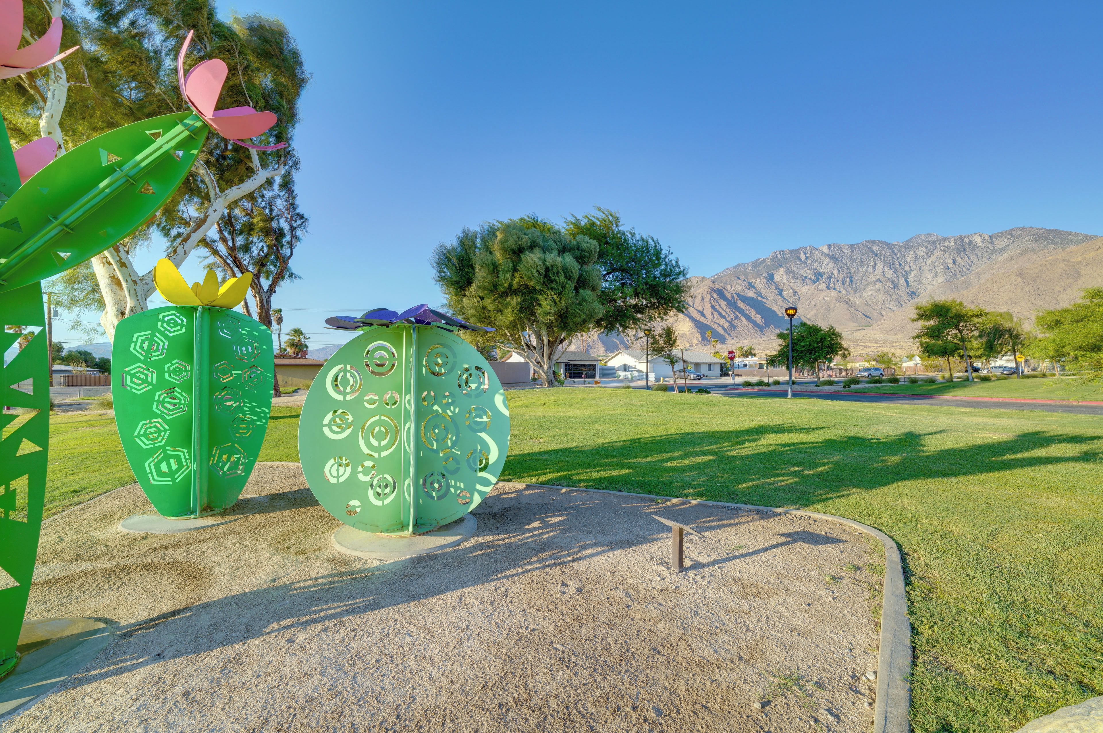 A park with green sculptures and a mountain in the background.