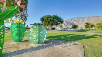 A park with green sculptures and a mountain in the background.