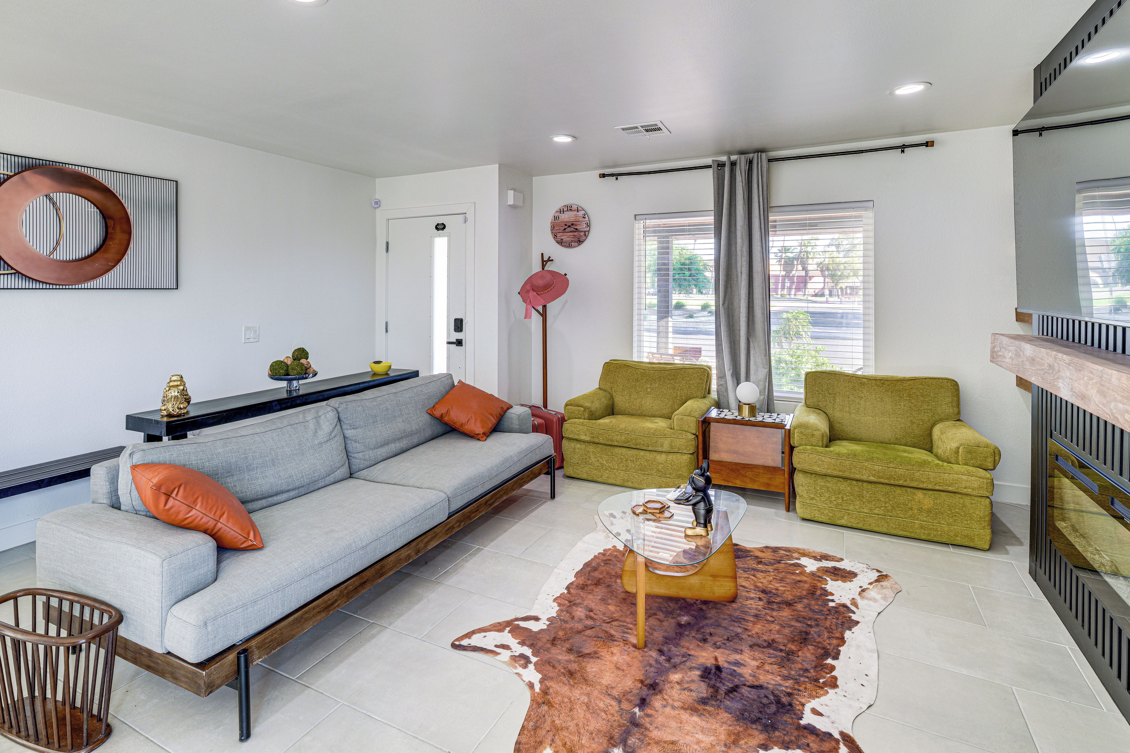 Una sala de estar moderna con un sofá, dos sillones, una mesa de centro y un tapete de cuero de vaca.