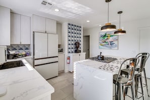 A modern kitchen with a central island, stainless steel appliances, and a coffee bar.