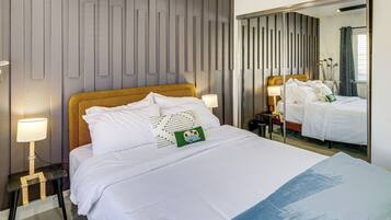 Une chambre d’hôtel avec un grand lit, des lampes de chevet, un miroir et une vue sur l’extérieur.