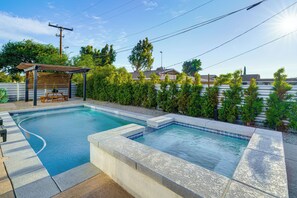 A rectangular swimming pool with a wooden deck and a pergola, surrounded by a landscaped garden and residential buildings. - Remodeled Home w/ Mtn Views in Palm Springs! (Palm Springs)