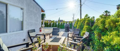 Een terras met buitenmeubilair, een brandblusser en uitzicht op de omliggende groene omgeving en gebouwen.