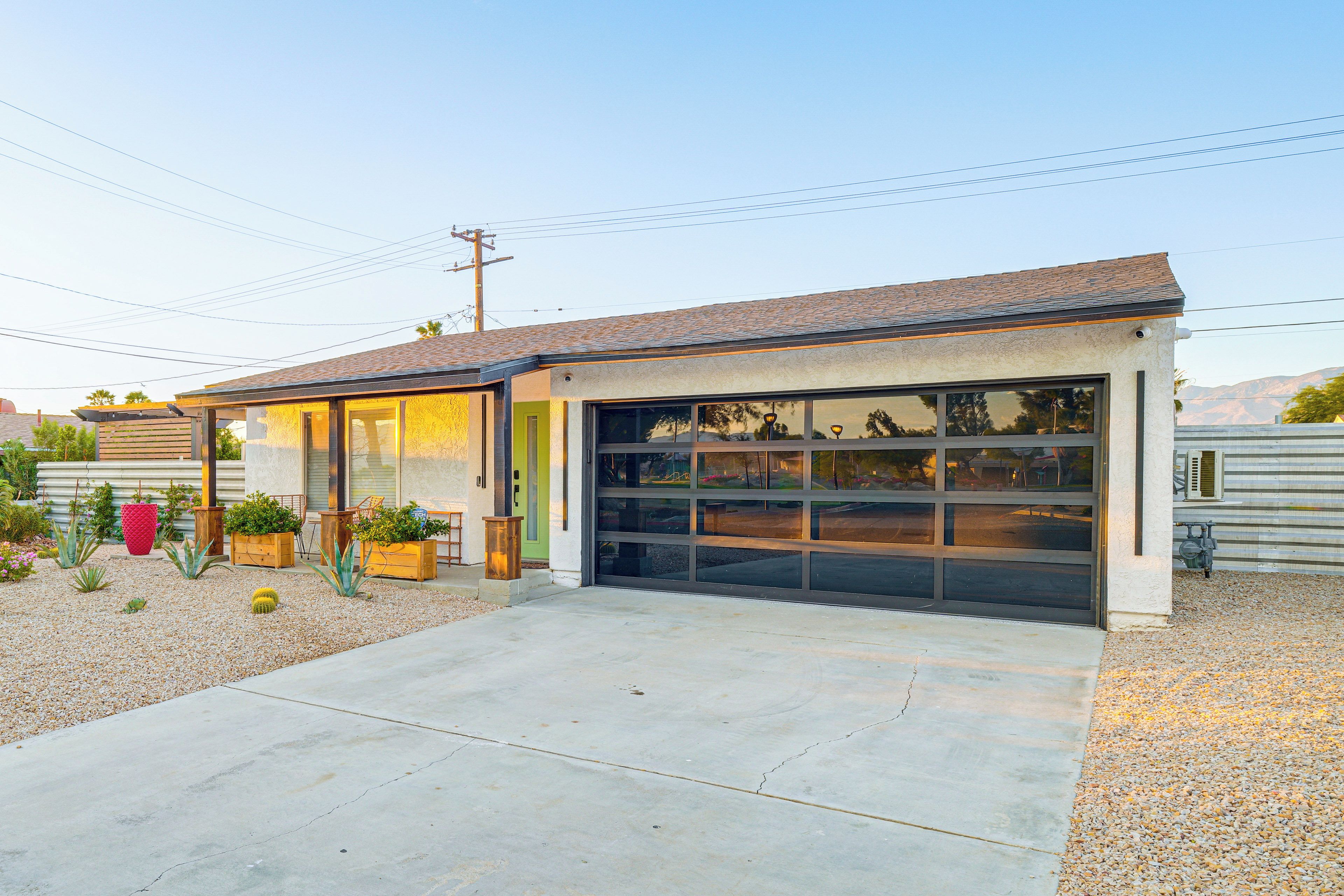 A single-story house with a garage, a small patio area with potted plants, and a clear sky.
