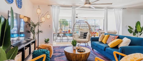 A modern living room with a blue sofa, a wooden coffee table, and a ceiling fan.
