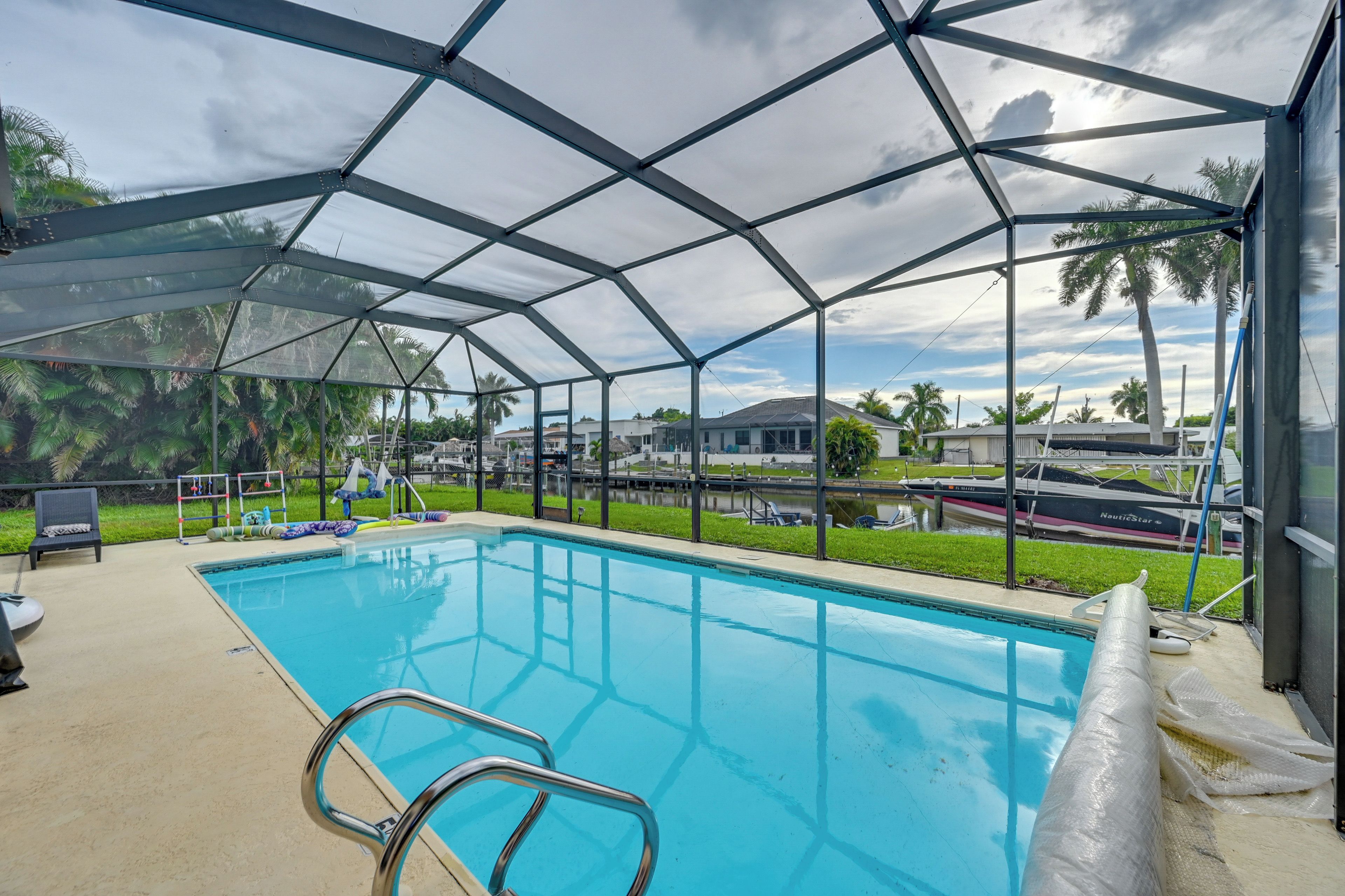 A covered swimming pool with a metal frame and a view of the surrounding area including houses and a body of water.